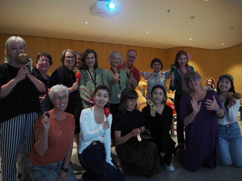Group together posing for photo holding maraccas and other small musical instruments