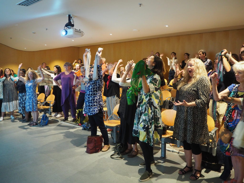 Audience standing up and putting hands in the air looking happy