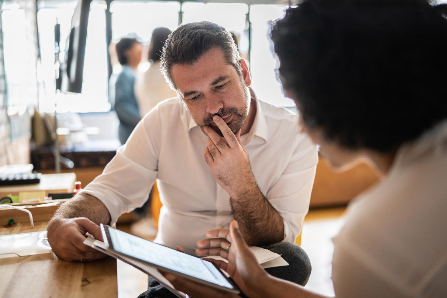 Two professionals reviewing information together on a tablet during a meeting.